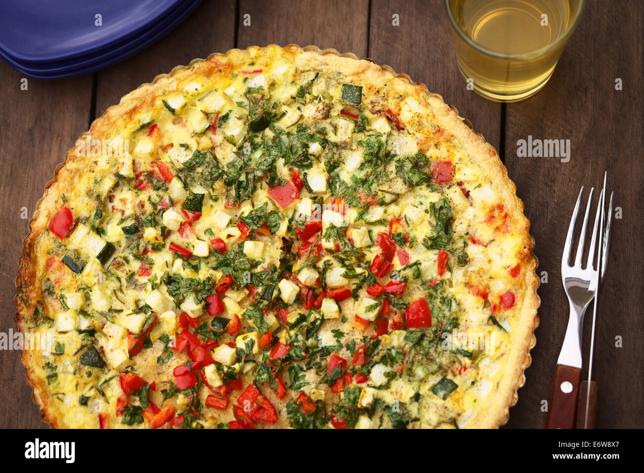 In casa vegetarian quiche con zucchine, il peperone rosso e prezzemolo in una teglia Foto Stock