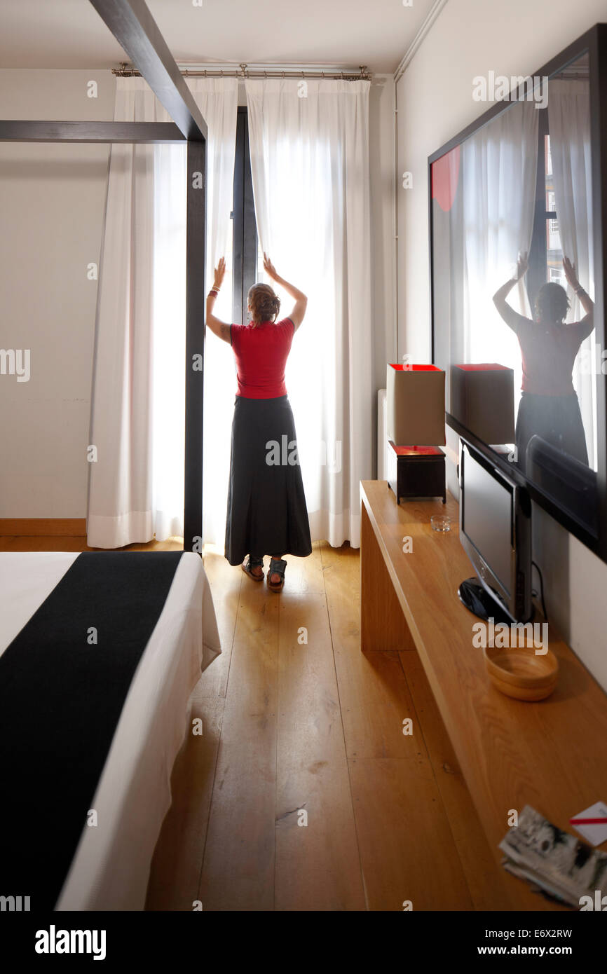 Donna in piedi alla finestra di una camera standard in Hotel Market, Comte Borrell 68, Barcellona, Spagna Foto Stock