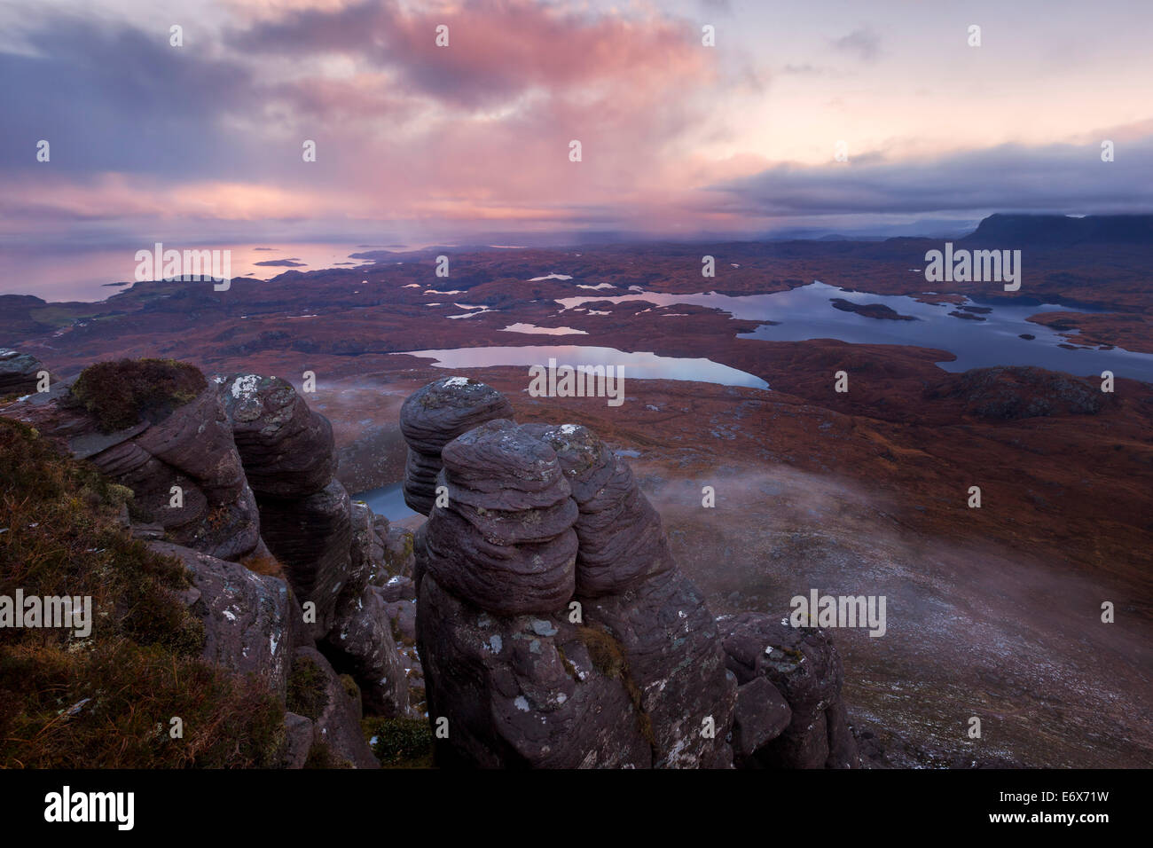 Alba con la vista da stac Pollaidh oltre l'Inverpolly Riserva Naturale con tipiche formazioni arenarie in primo piano Foto Stock