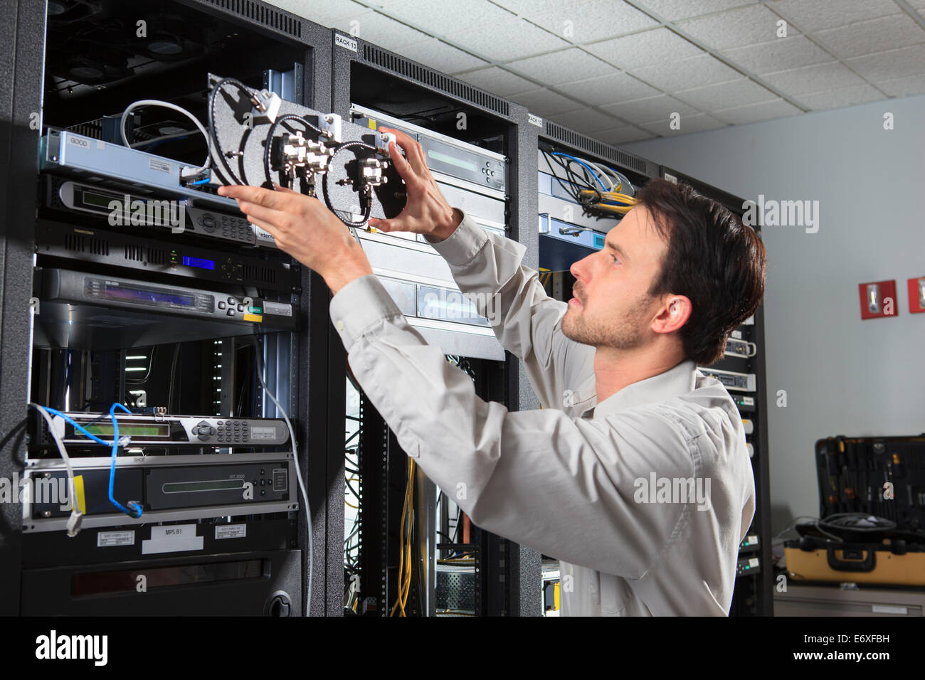 Ingegnere di rete mettendo montato su rack switch coassiale al posto Foto Stock