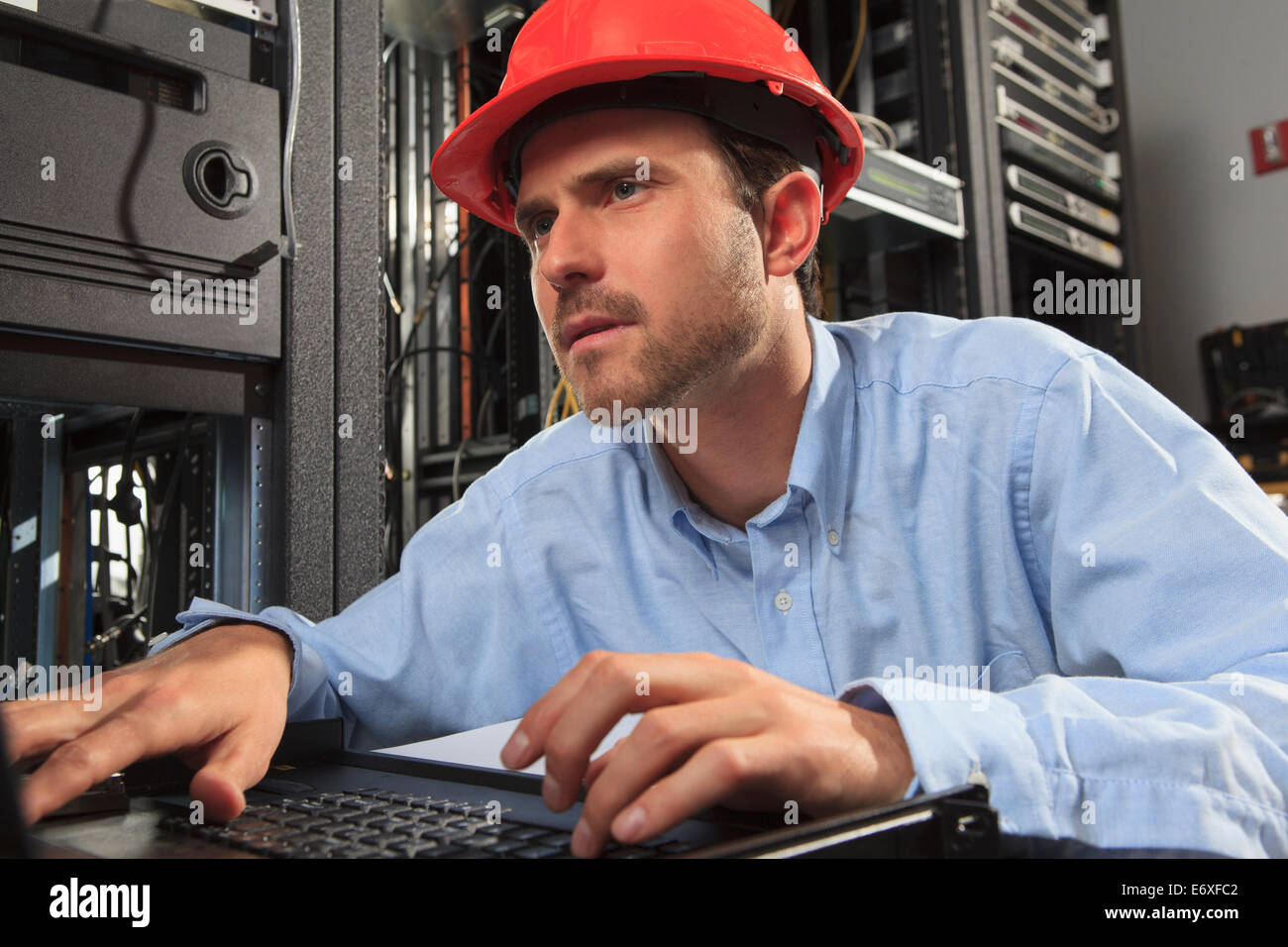 Ingegnere di rete esaminando la configurazione del sistema alla tastiera Foto Stock