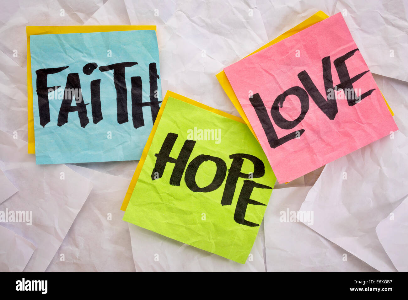 La fede, amore e speranza - colorata sticky notes su uno sfondo di accartocciata note bianco Foto Stock