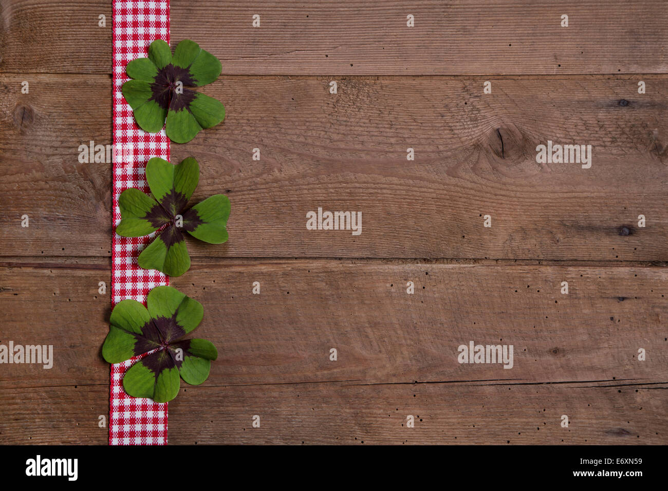 Sfondo di legno con il rosso e bianco nastro a scacchi e trifogli di verde per un felice anno nuovo Foto Stock