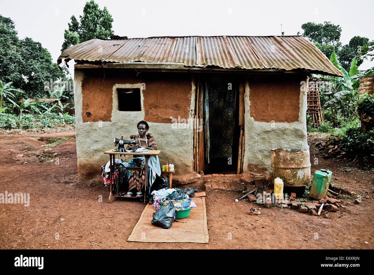 La donna la cucitura nella parte anteriore del suo rifugio, Buwenda, Uganda, Africa Foto Stock La donna la cucitura nella parte anteriore del suo rifugio, Buwenda, Uganda, Africa Foto Stock