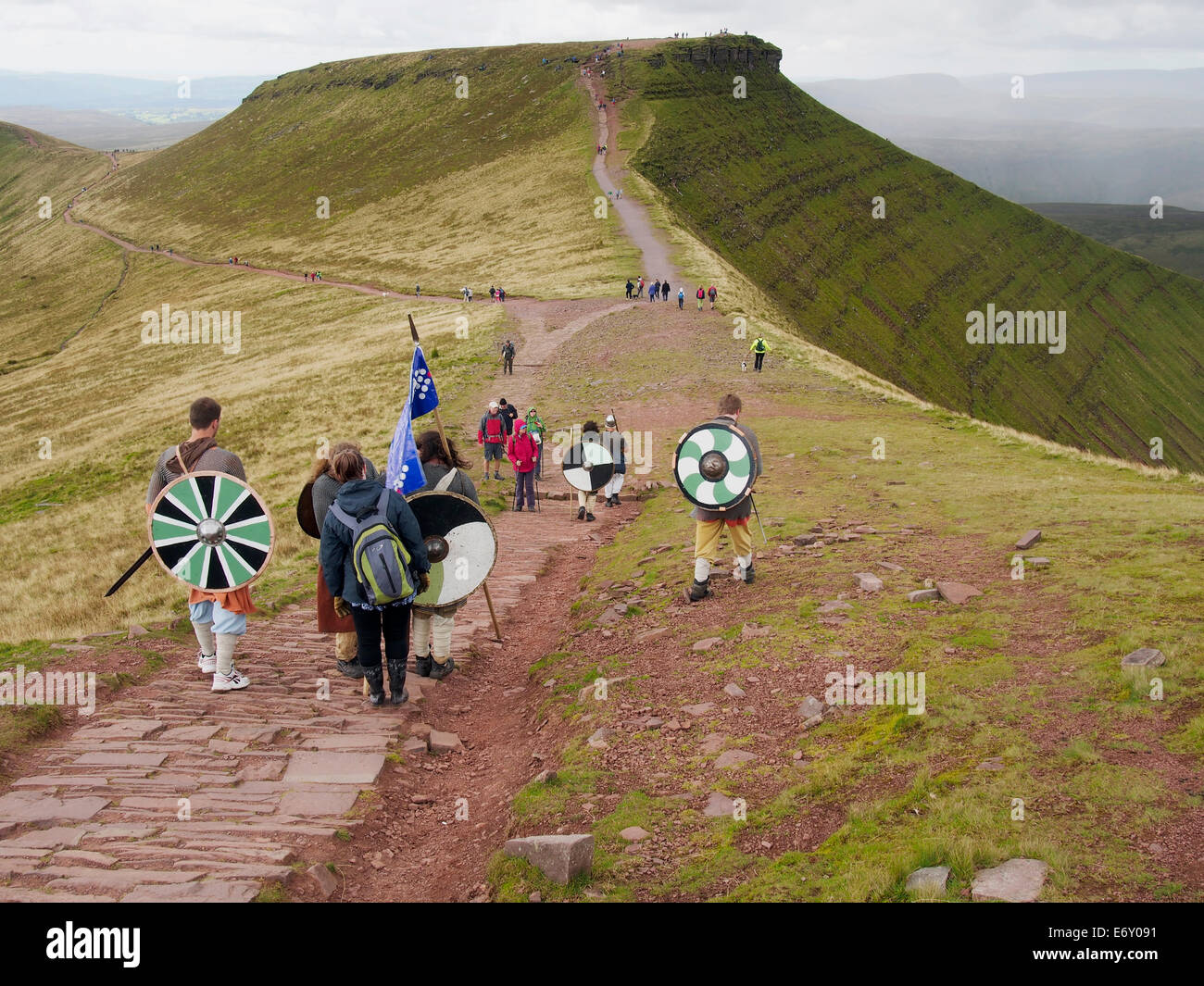 Passeggiate in collina in Brecon Beacons. Un gruppo di escursionisti di beneficenza in abito celtico sul sentiero da Pen y la ventola con il Mais Du avanti Foto Stock
