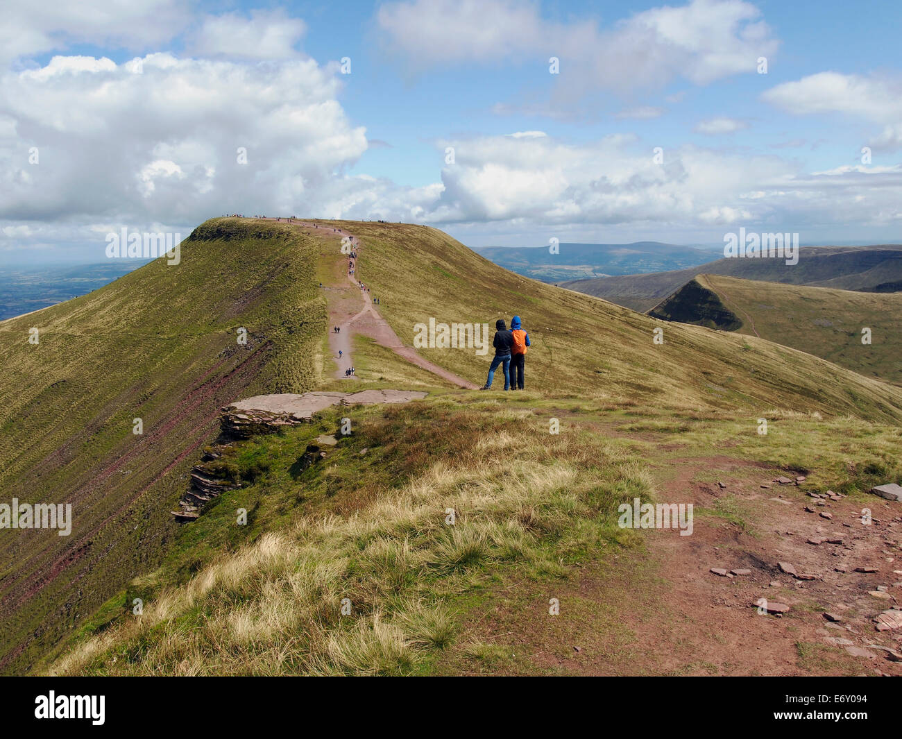 Passeggiate in collina in Brecon Beacons. Walkers sul vertice di mais Du guardare attraverso il col al picco della penna ventola y. Foto Stock