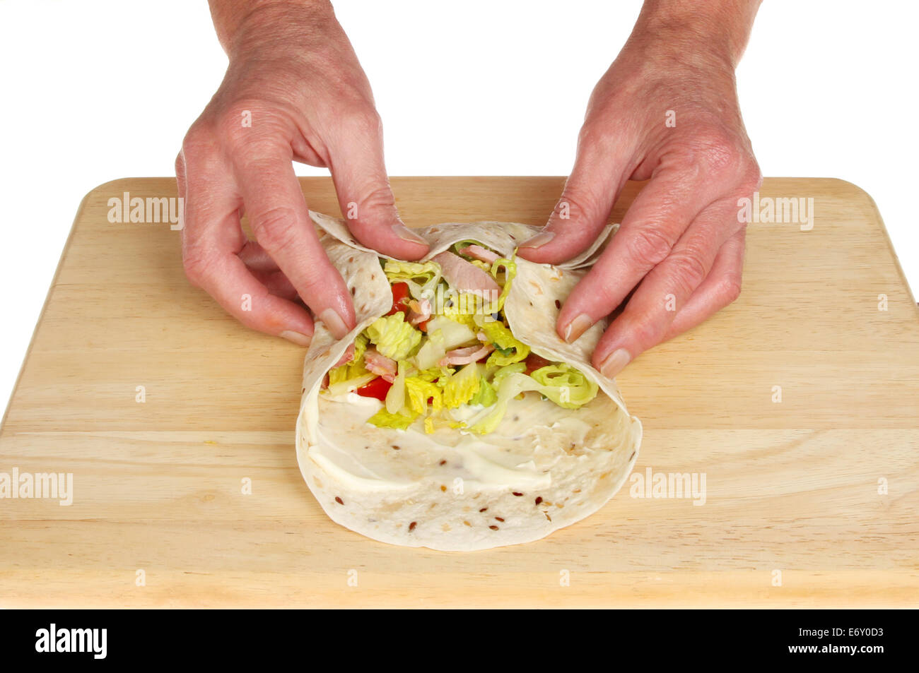Le mani facendo una pancetta insalata e pane avvolgere su una tavola di legno Foto Stock