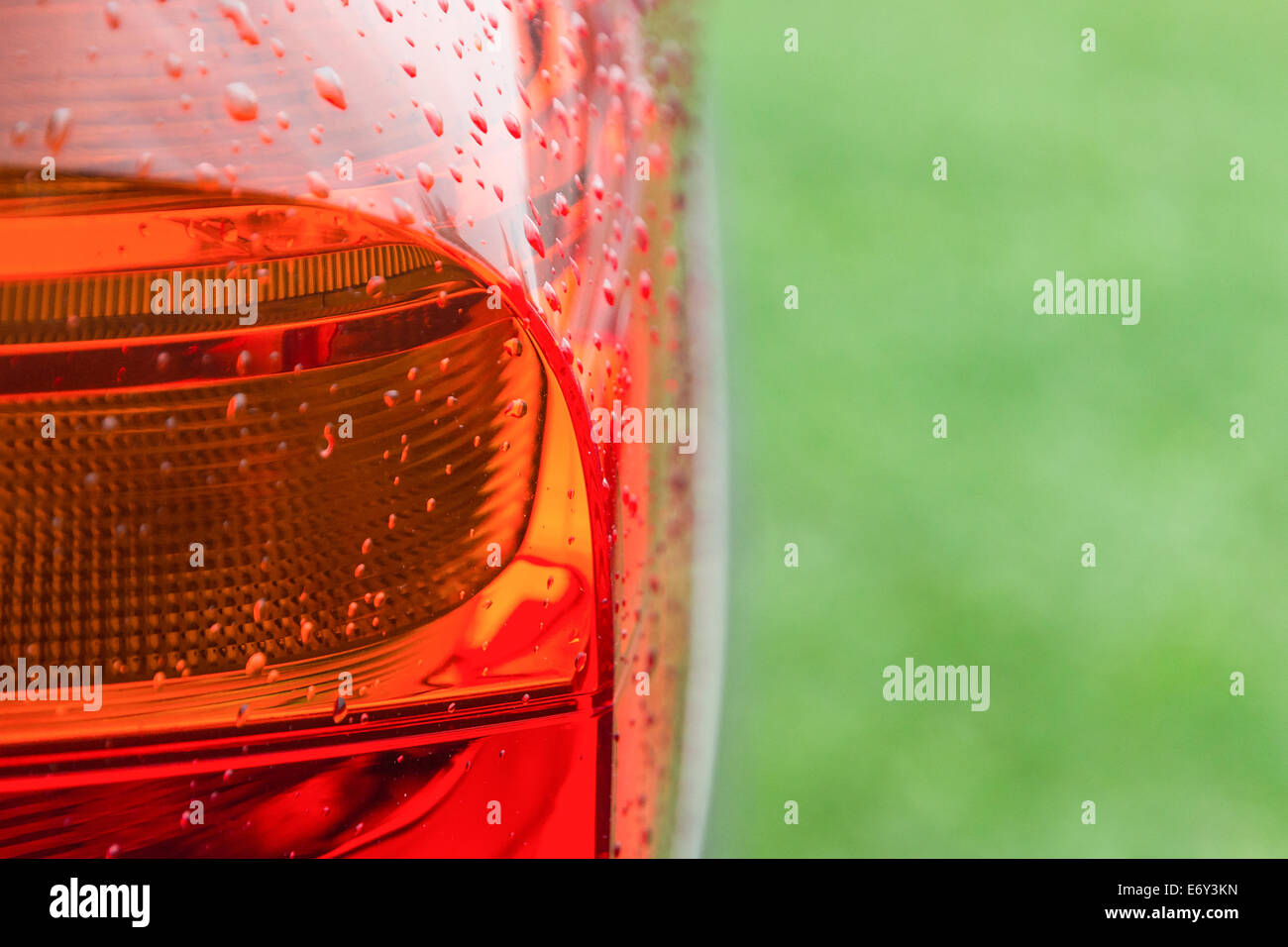 Bagnate dopo la pioggia con gocce d'acqua le luci di coda della nuova vettura moderna su fresco verde erba Foto Stock