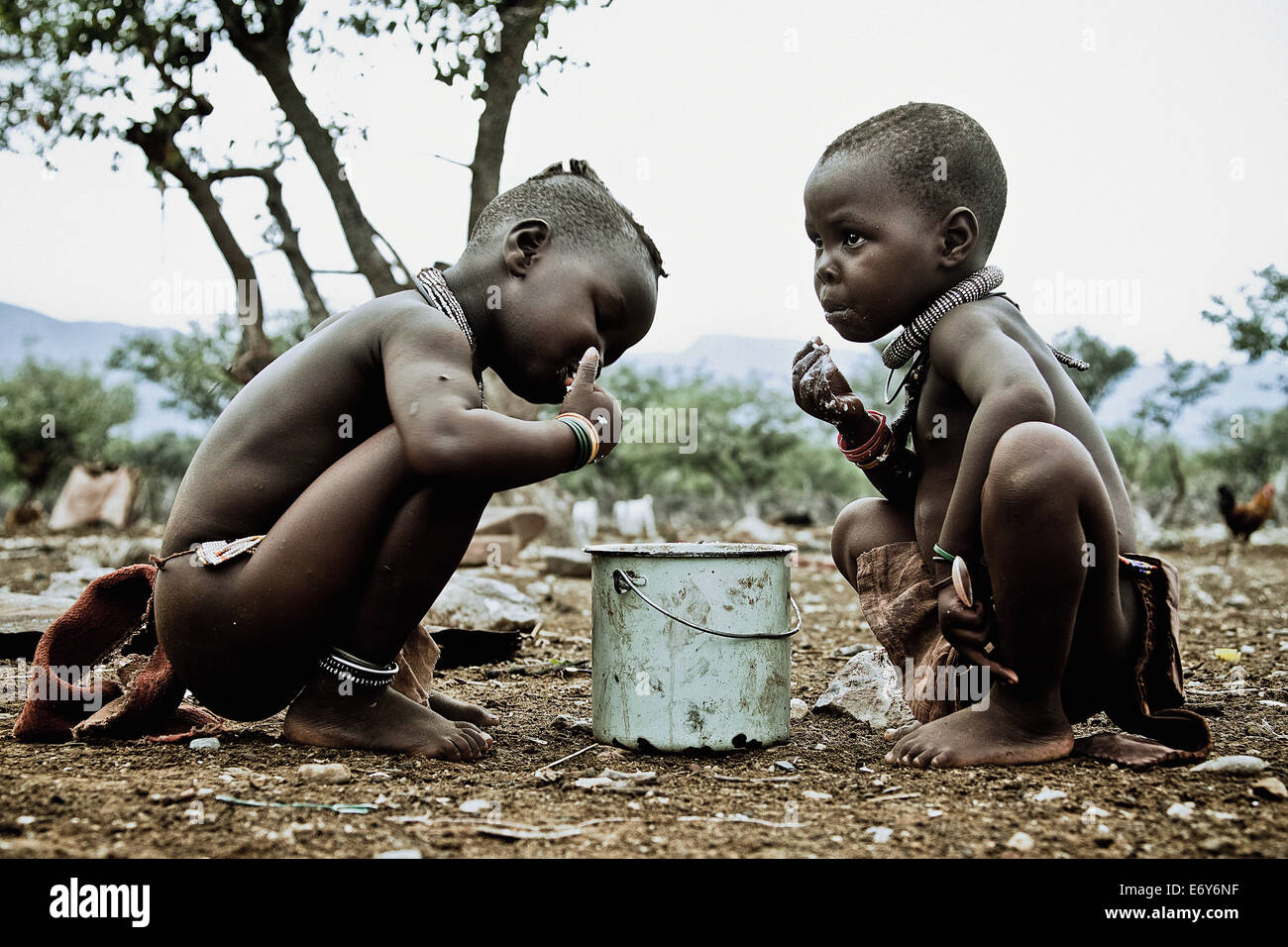 Due bambini della tribù Himba mangiare fuori di una pentola, Kaokoland, Namibia, Africa Foto Stock