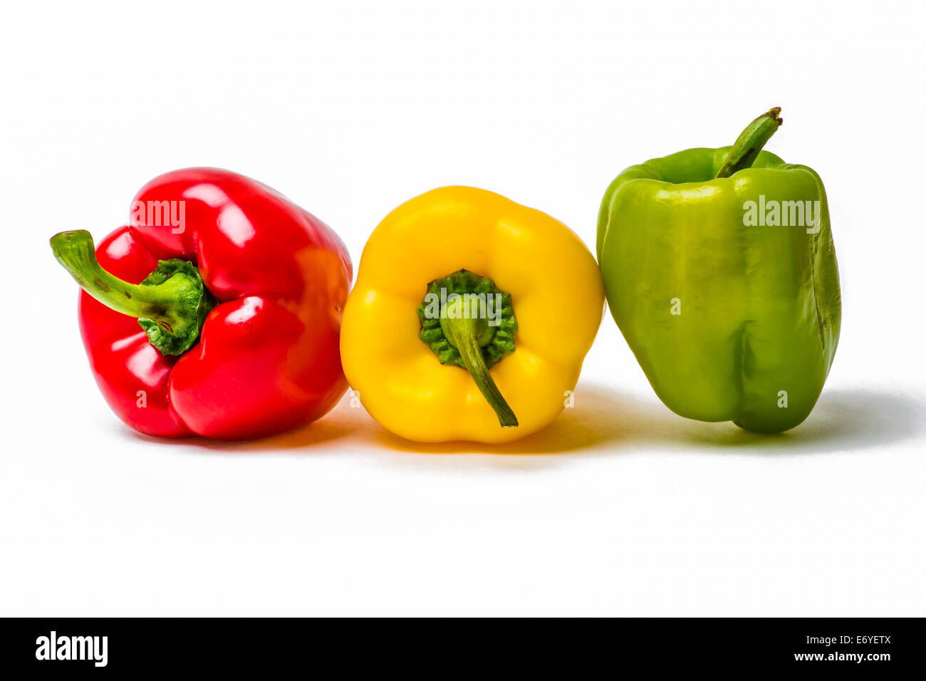 Rosso, giallo e peperoni verdi in una riga isolata contro lo sfondo bianco Foto Stock