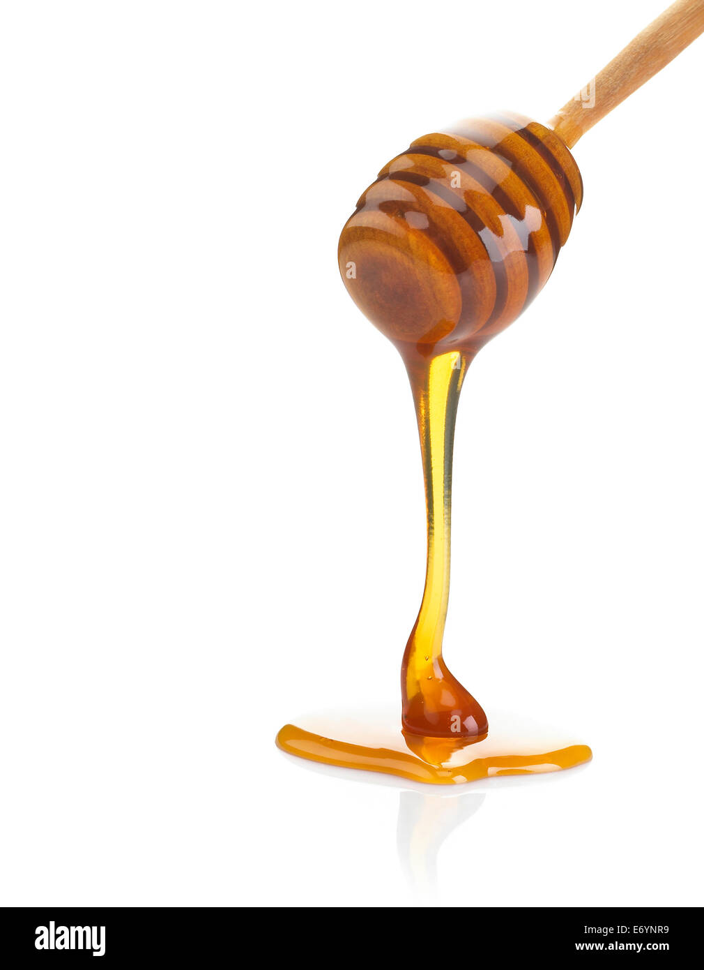 Foto di miele gocciolare da un bilanciere in legno isolato su uno sfondo bianco. Foto Stock