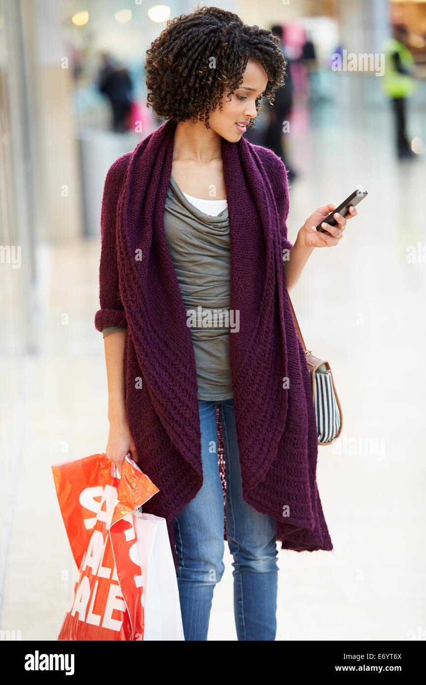 La donna nel Centro Commerciale per lo Shopping tramite telefono cellulare Foto Stock