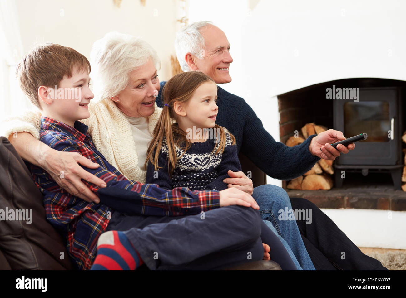 Nonni seduti sul divano a guardare la TV con i nipoti Foto Stock