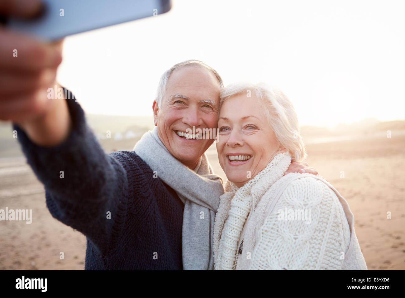 Coppia senior permanente sulla spiaggia prendendo Selfie Foto Stock