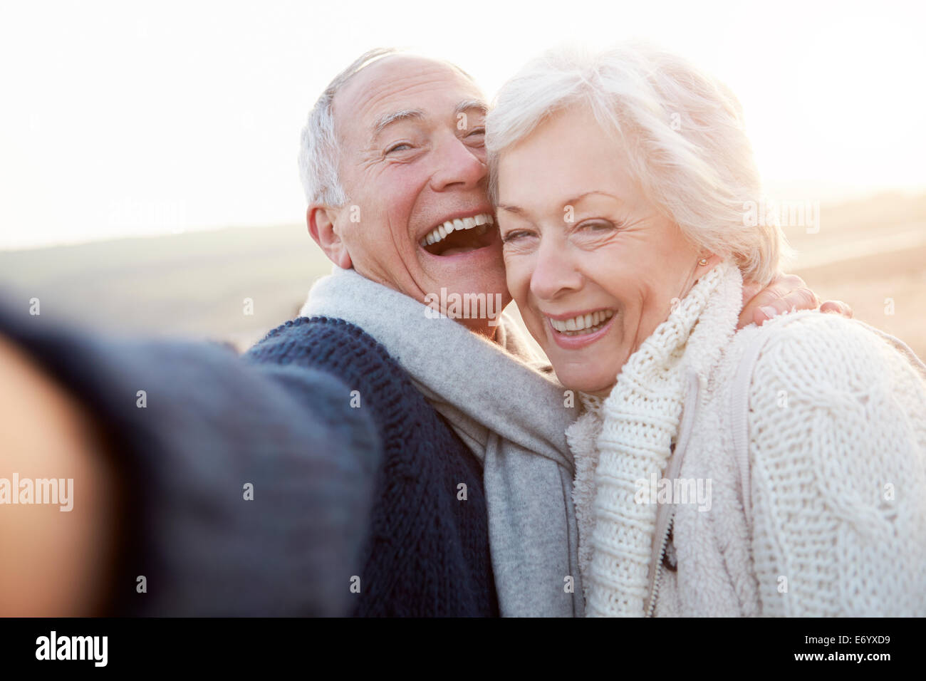 Coppia senior permanente sulla spiaggia prendendo Selfie Foto Stock