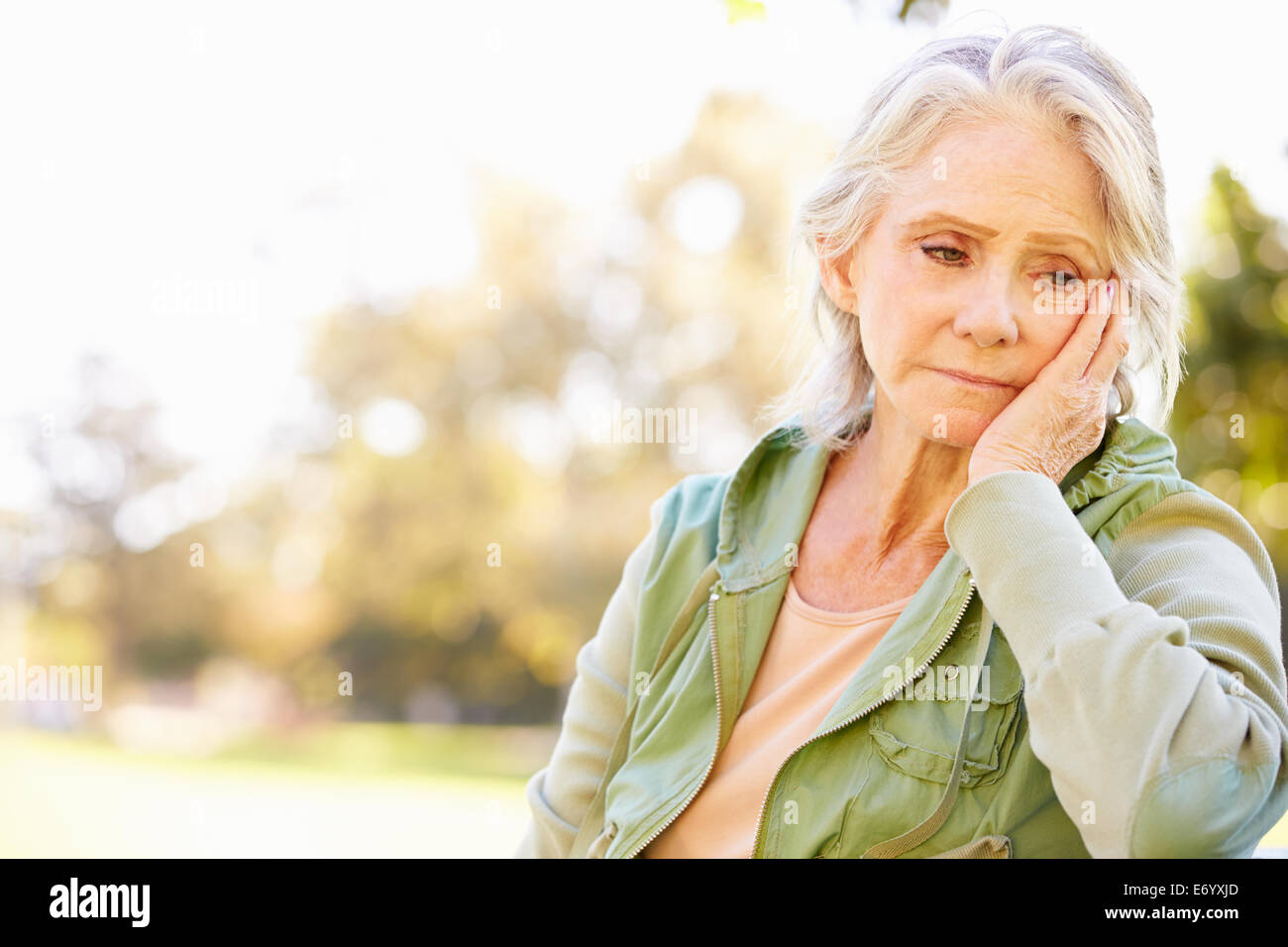 Premuto Senior donna seduta al di fuori Foto Stock