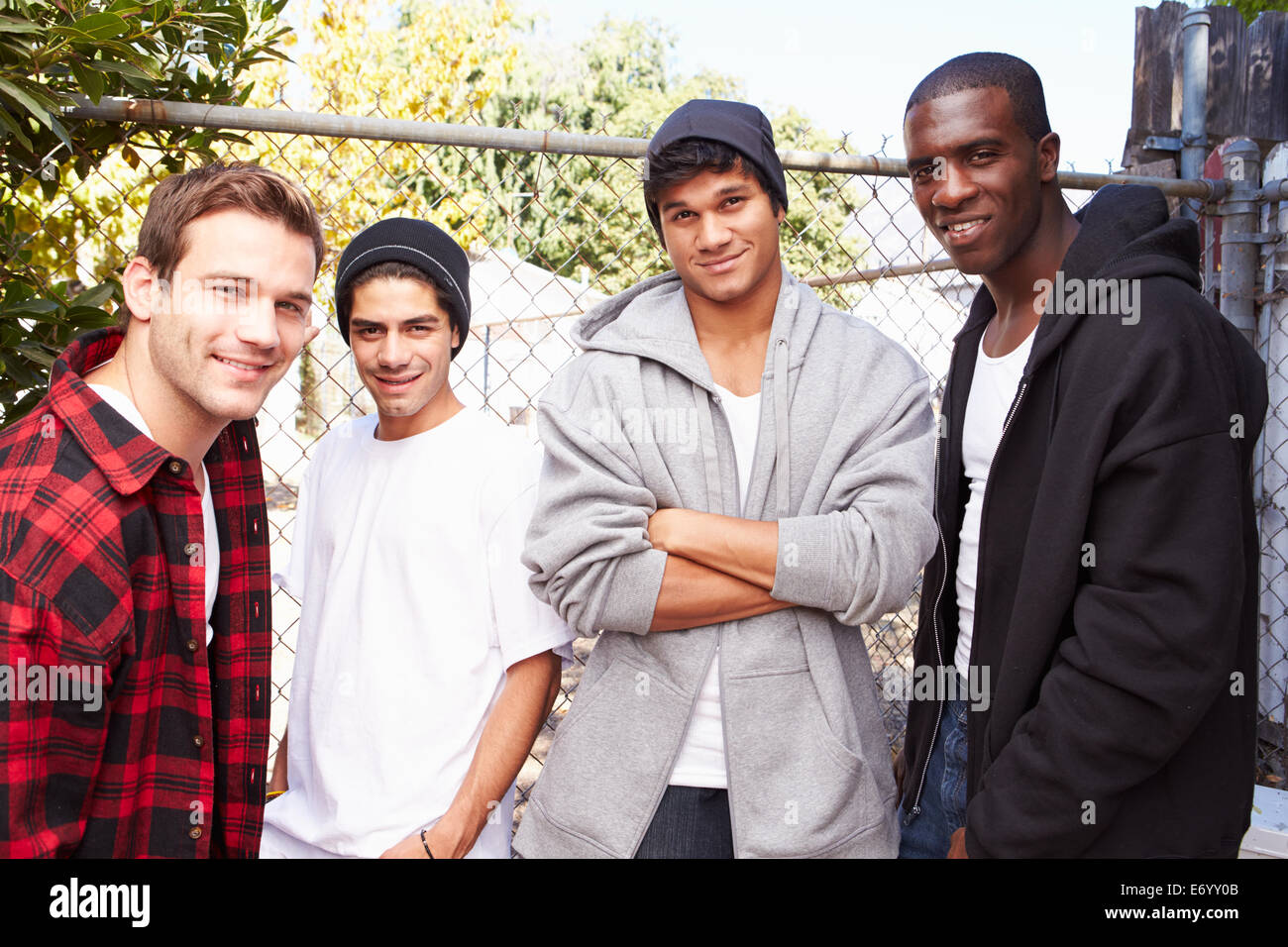 Un gruppo di giovani uomini in assetto urbano in piedi da recinzione Foto Stock