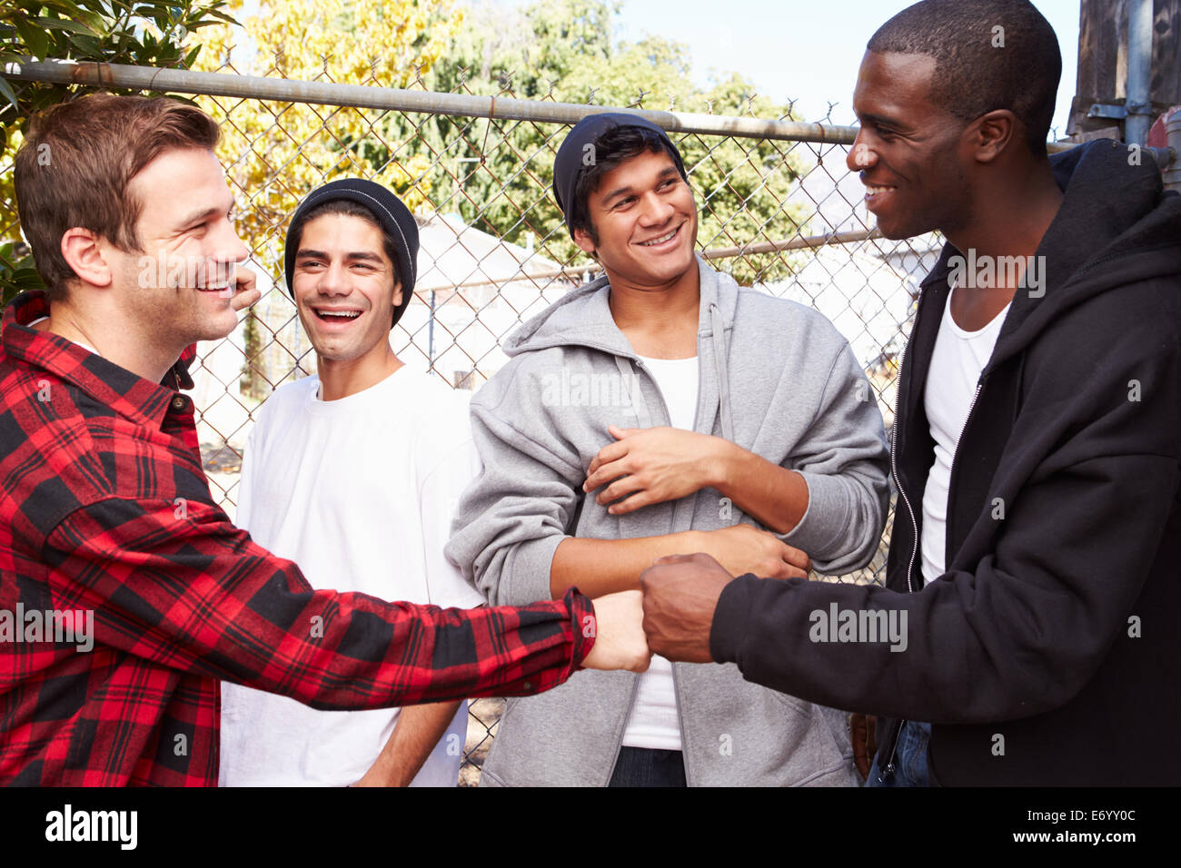 Un gruppo di giovani uomini saluto uno un altro nel contesto urbano Foto Stock
