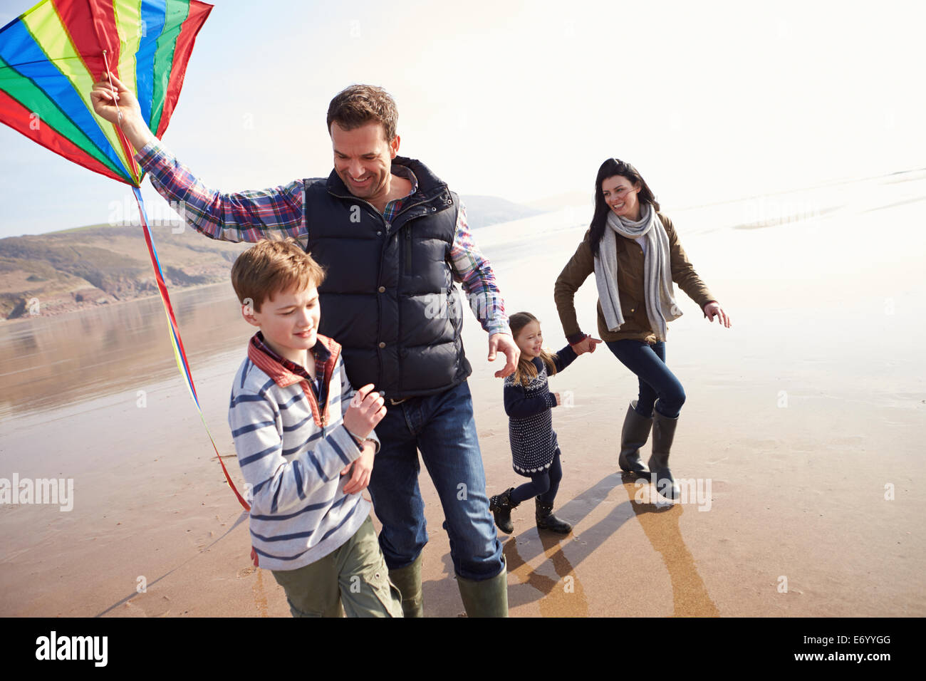La famiglia lungo la spiaggia invernale aquilone volante Foto Stock
