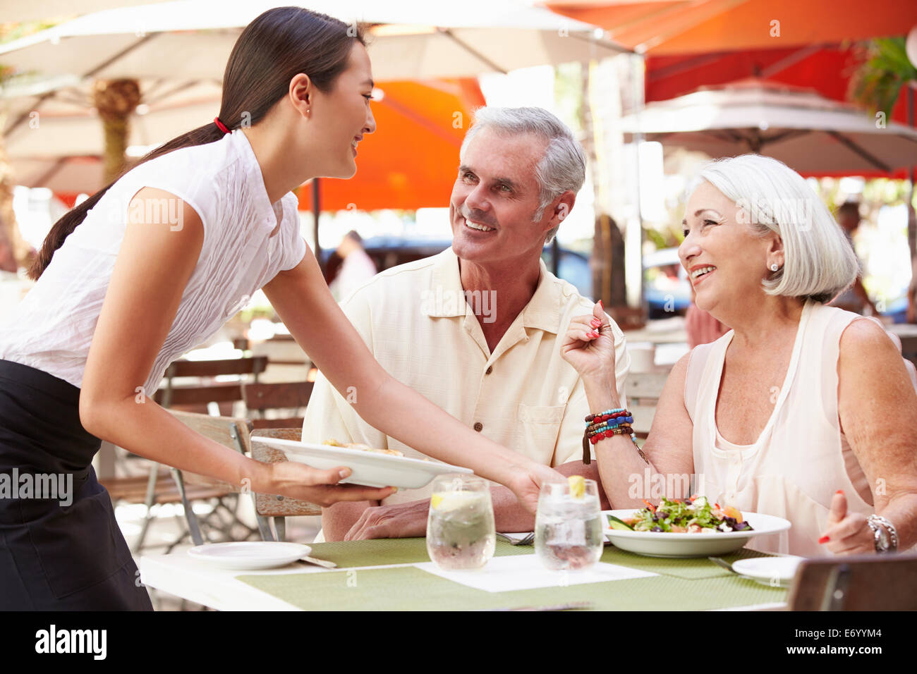 Cameriera serve coppia Senior il pranzo in un ristorante esterno Foto Stock