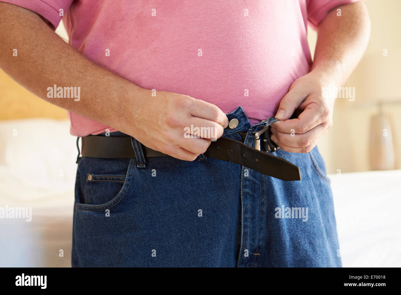 Close Up di sovrappeso uomo cercando di allacciare i pantaloni Foto Stock
