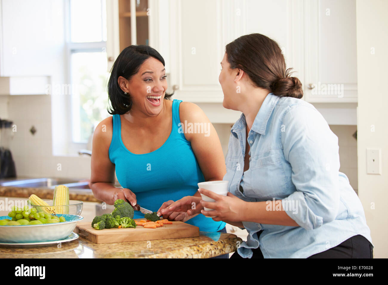 Due donne in sovrappeso sulla dieta preparare verdure in cucina Foto Stock