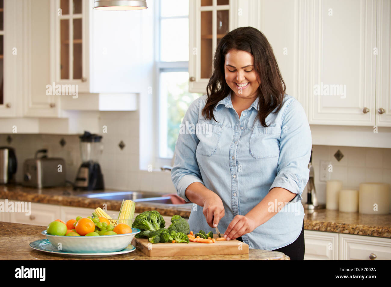 Donna sovrappeso preparare verdure in cucina Foto Stock