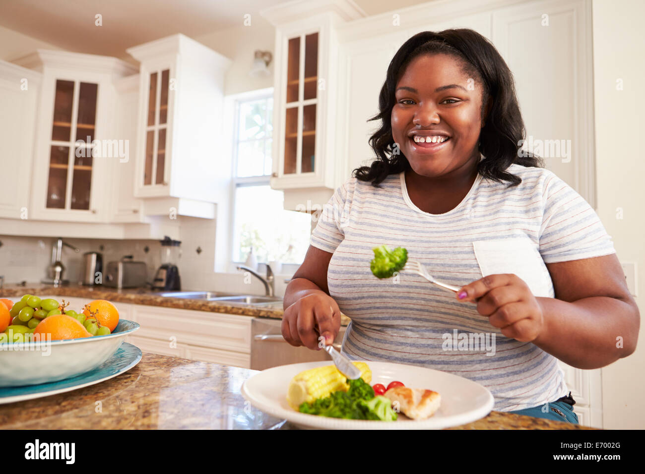 Donna sovrappeso mangiare sano pasto in cucina Foto Stock