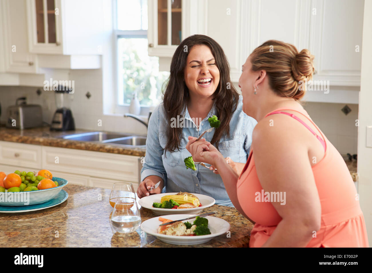 Due donne in sovrappeso sulla dieta mangiare sano pasto in cucina Foto Stock