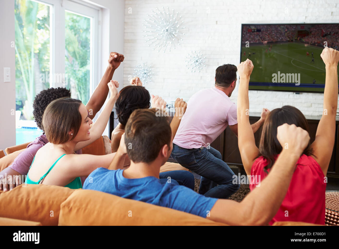 Gruppo di amici guardare partite di calcio celebrando obiettivo Foto Stock