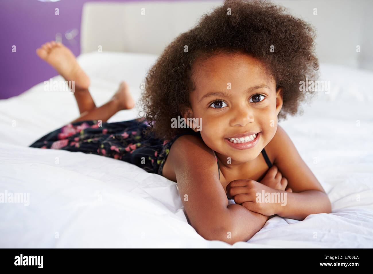 Carino Bambina giacente sulla pancia in letto con i genitori Foto Stock
