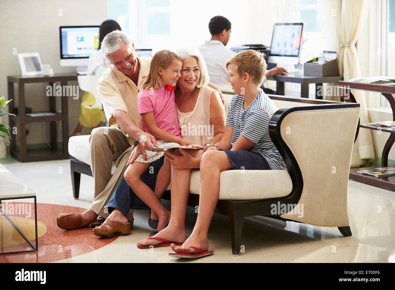 Nonni con i nipoti seduti nella Hall Hotel Foto Stock
