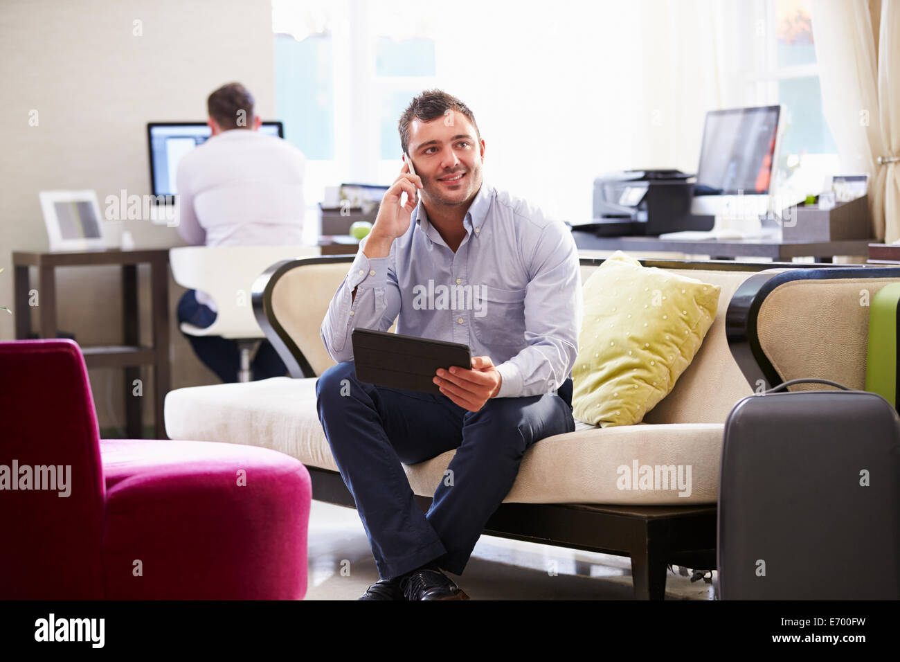 Imprenditore lavora su tavoletta digitale nella Hall Hotel Foto Stock