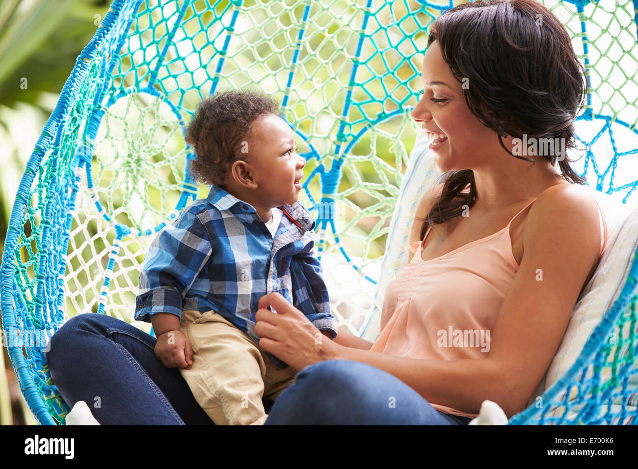 Madre con bambino figlio sul rilassante giardino esterno del sedile oscillante Foto Stock