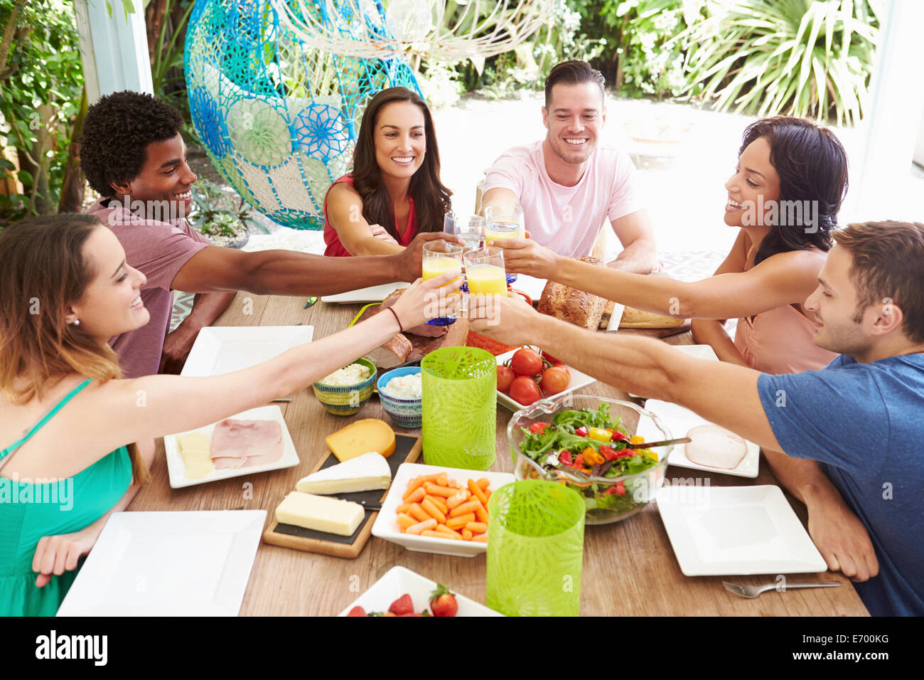 Gruppo di amici gustando pasti all'aperto a casa Foto Stock