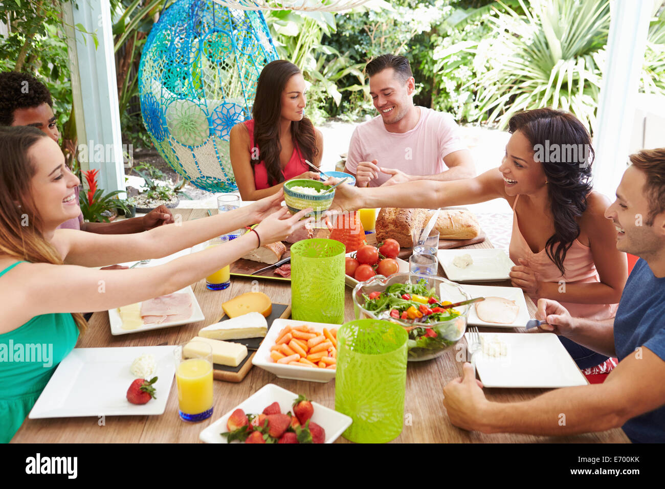 Gruppo di amici gustando pasti all'aperto a casa Foto Stock