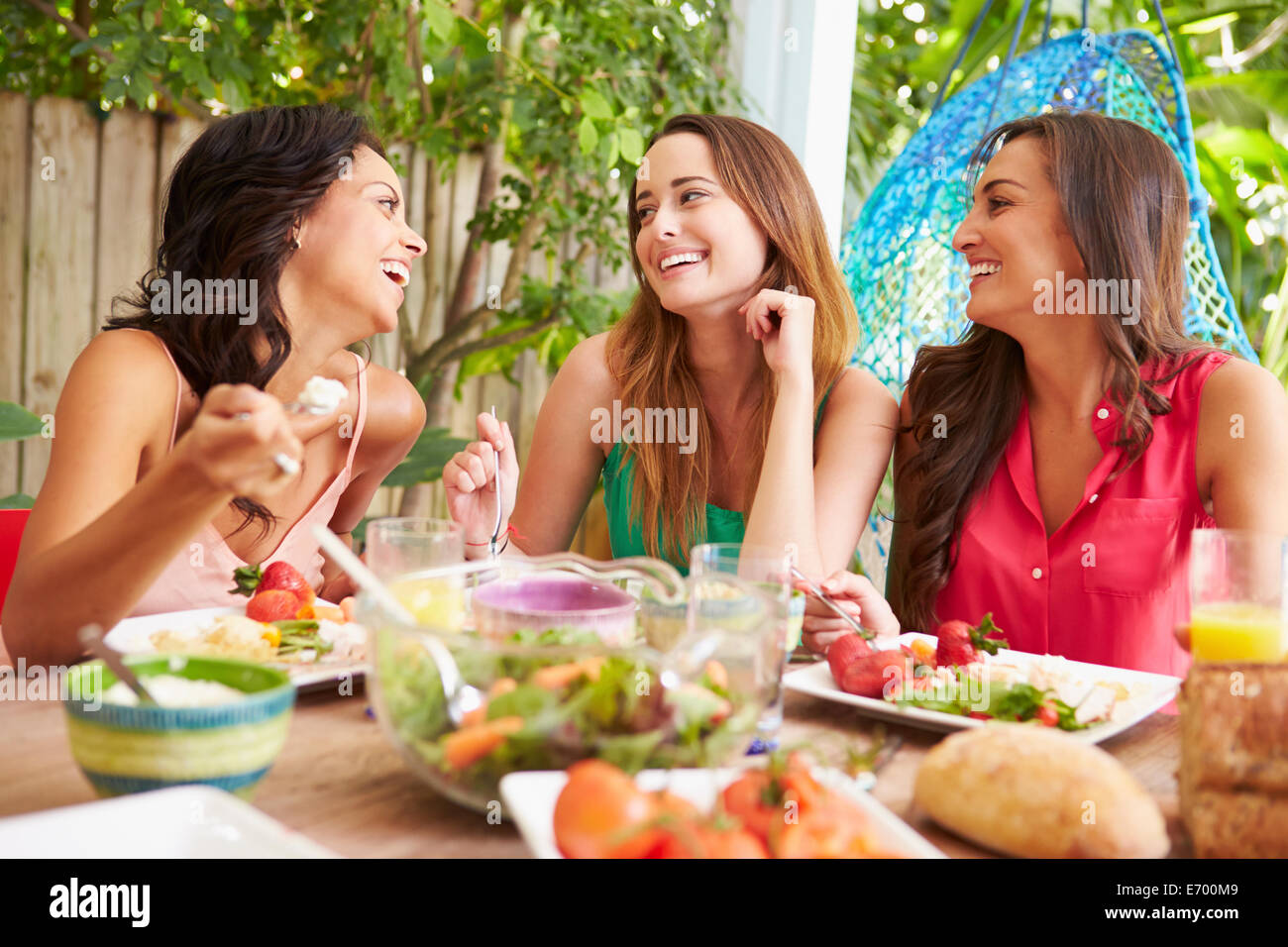 Tre Amiche godendo di pasto all'aperto a casa Foto Stock