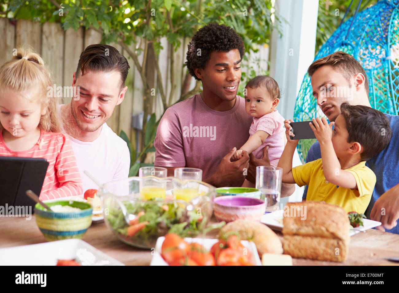 Gruppo di padri con i bambini all'aperto godendo di pasto a casa Foto Stock