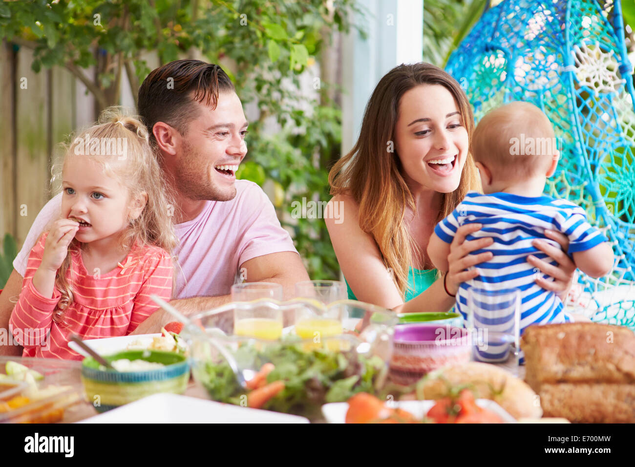 Famiglia all'aperto godendo di pasto a casa Foto Stock