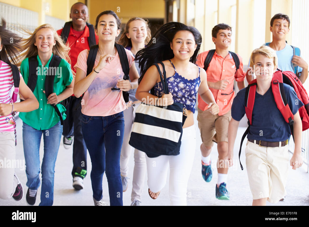 Un gruppo di studenti di scuola superiore che corre lungo il corridoio Foto Stock