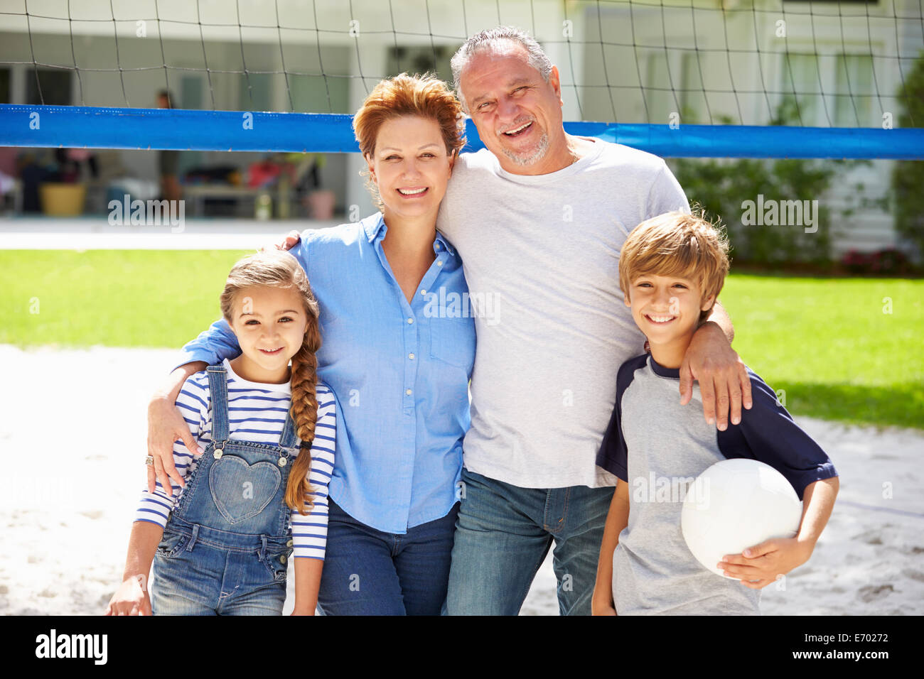Nonni e nipoti giocando a pallavolo in giardino Foto Stock