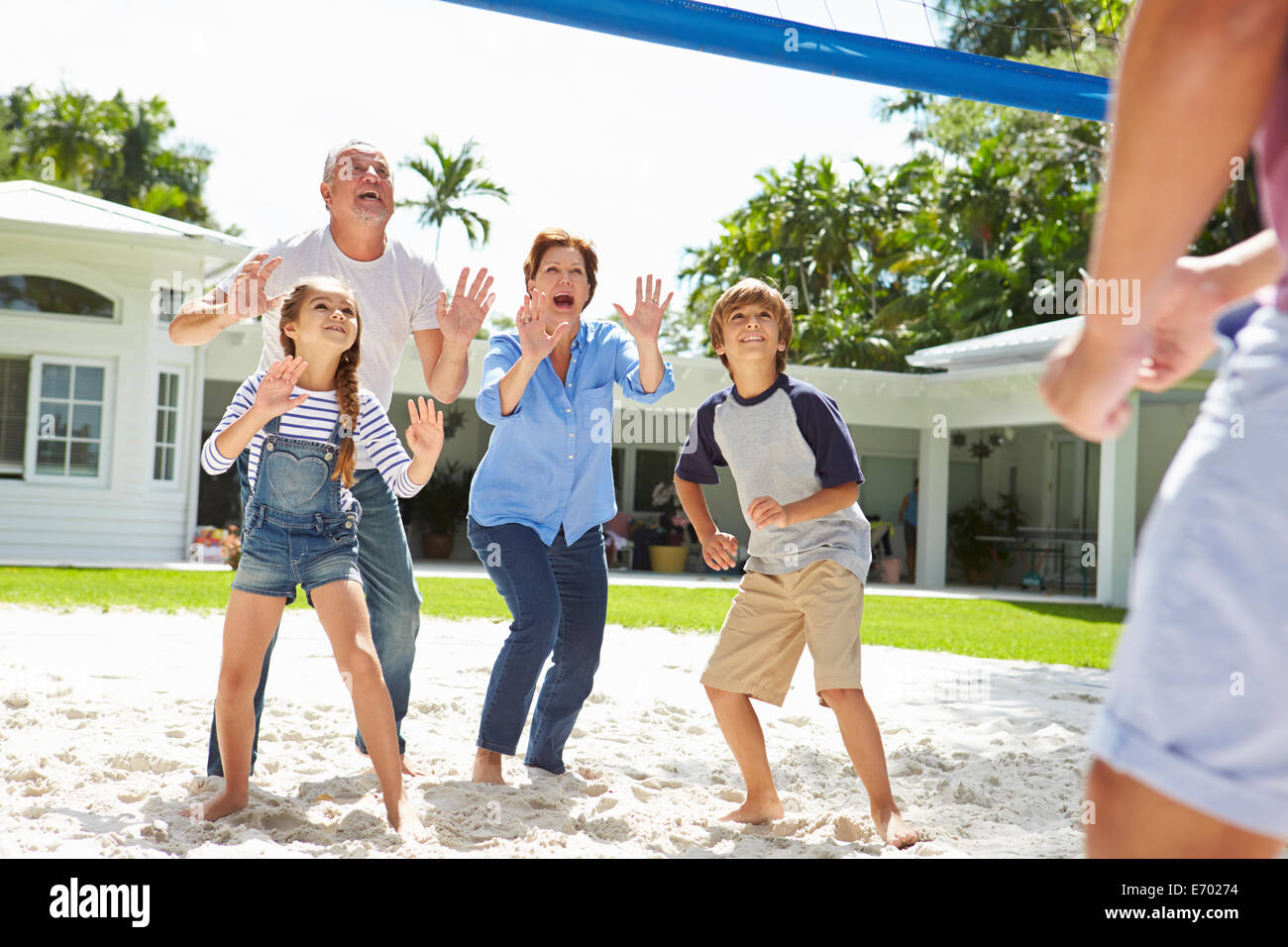 Nonni e nipoti giocando a pallavolo in giardino Foto Stock