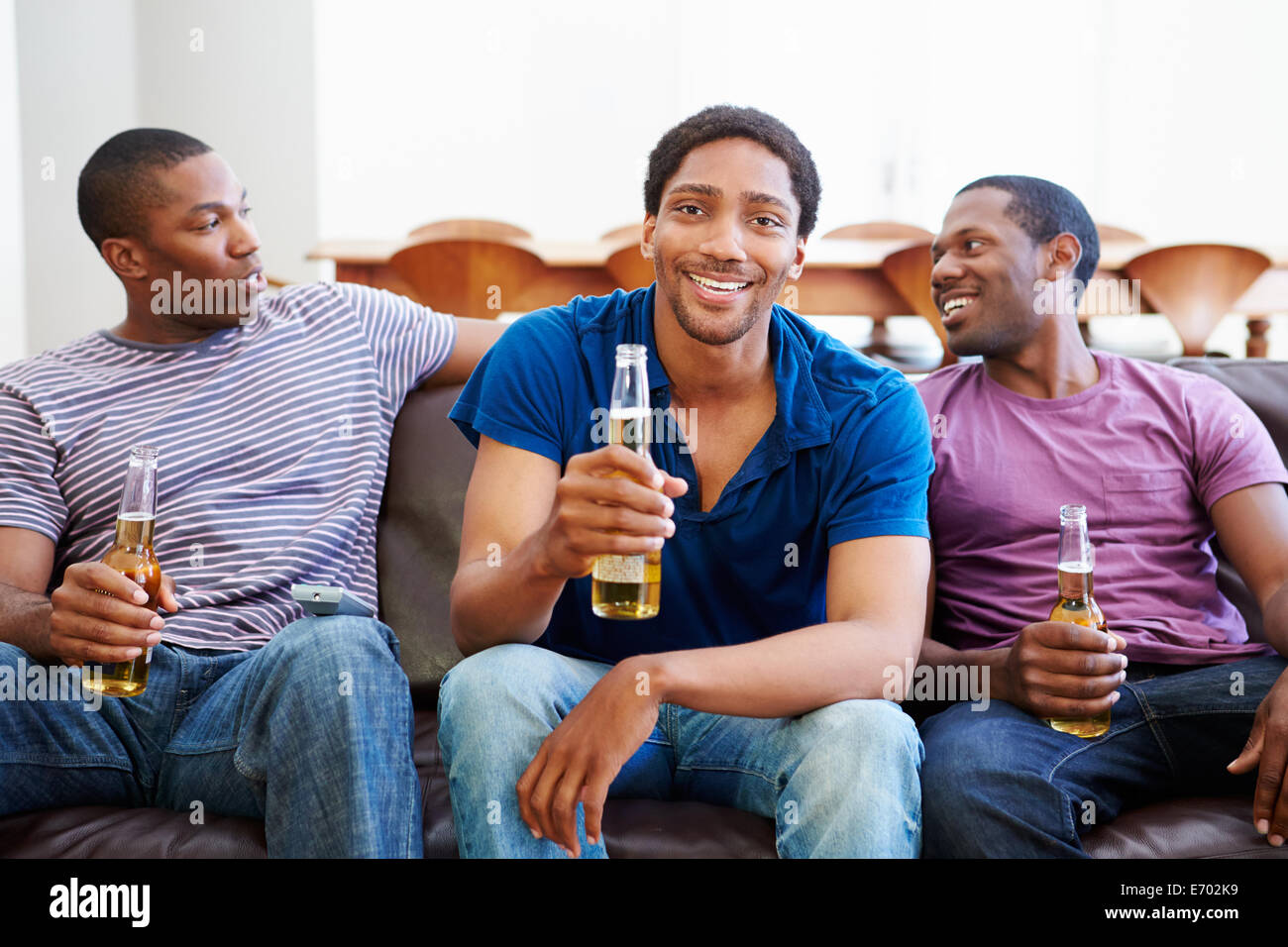 Un gruppo di uomini seduti sul divano guardando la TV insieme Foto Stock