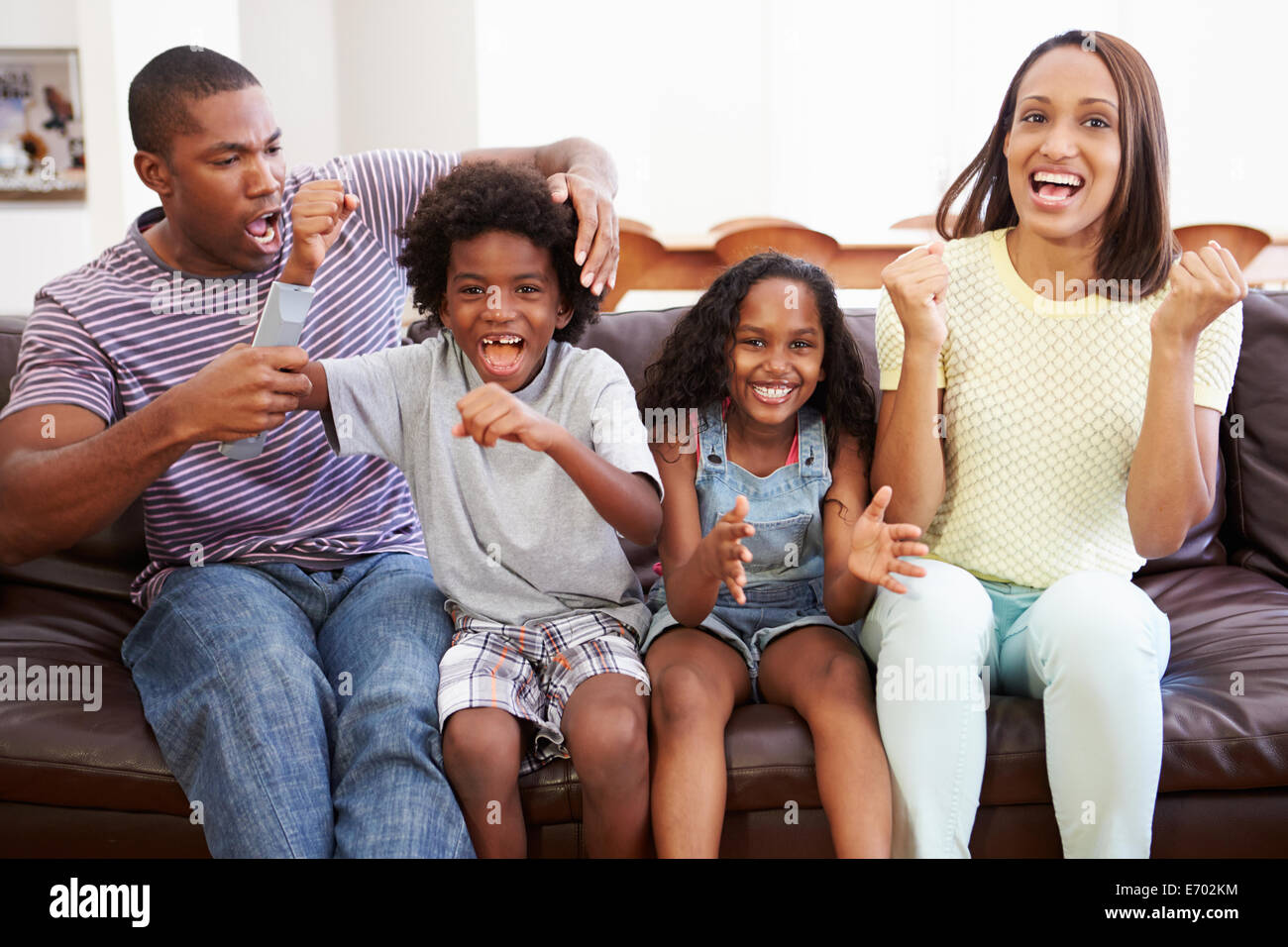 Famiglia seduti sul divano guardando la TV insieme Foto Stock