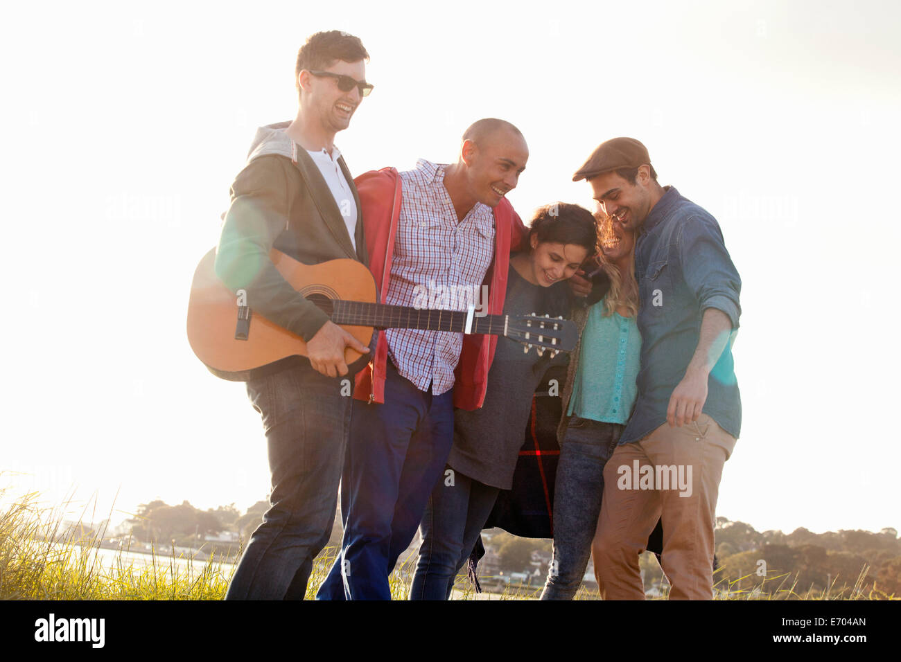 Cinque amici adulti con la chitarra acustica sulla spiaggia di Bournemouth Dorset, Regno Unito Foto Stock