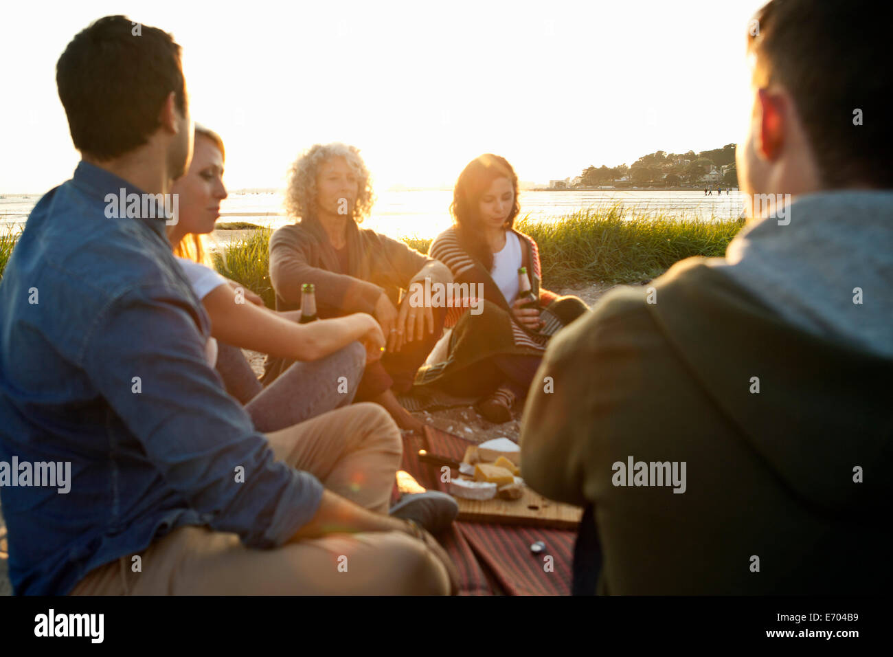 Cinque amici adulti aventi picnic sulla spiaggia di Bournemouth Dorset, Regno Unito Foto Stock