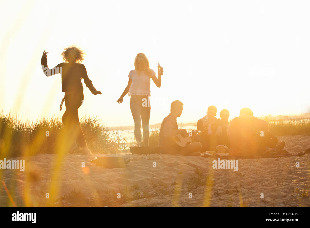 Sei amici adulti partying al tramonto sulla spiaggia di Bournemouth Dorset, Regno Unito Foto Stock