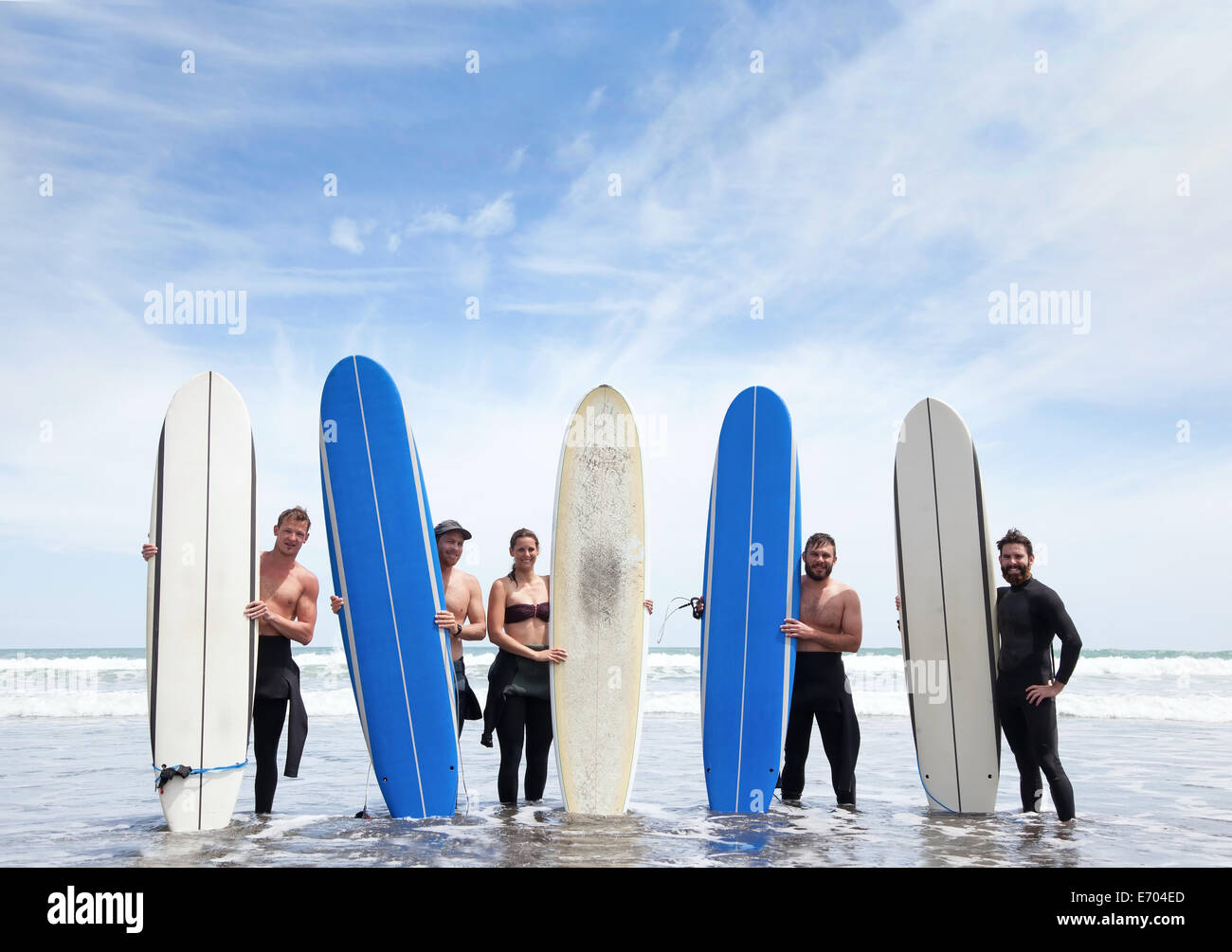 Ritratto di gruppo di maschio e femmina surfer amici stando in mare con tavole da surf Foto Stock