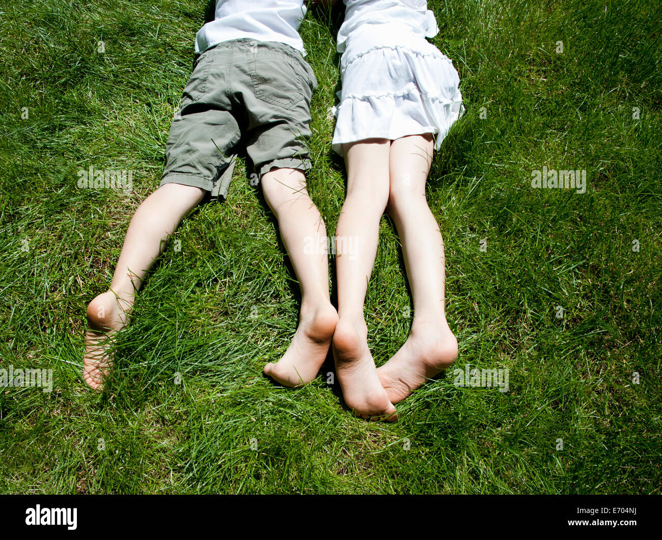 Vista aerea di fratelli e sorelle gambe come esse giacciono sull'erba Foto Stock