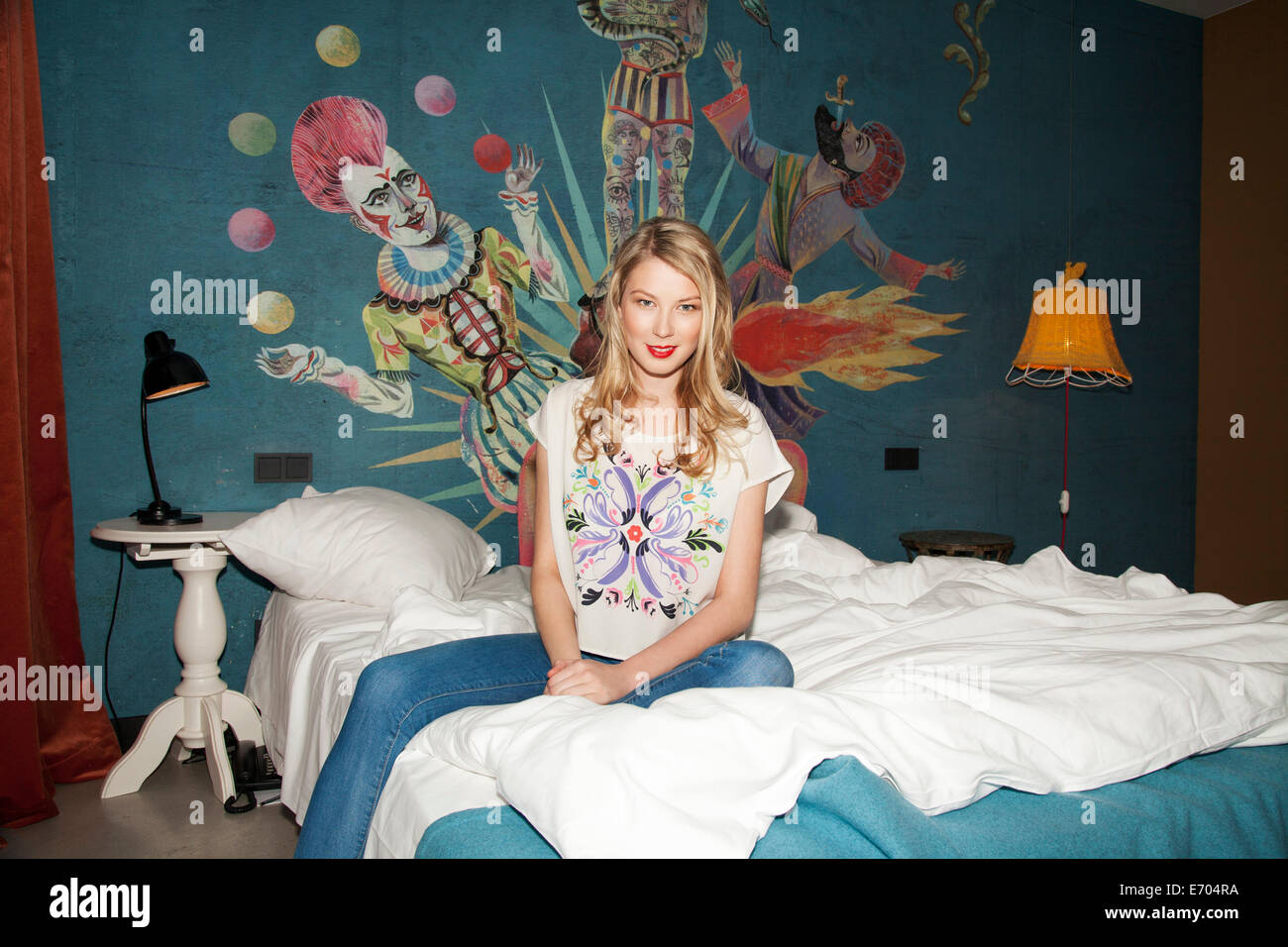 Ritratto di giovane donna seduta sul letto di hotel Foto Stock